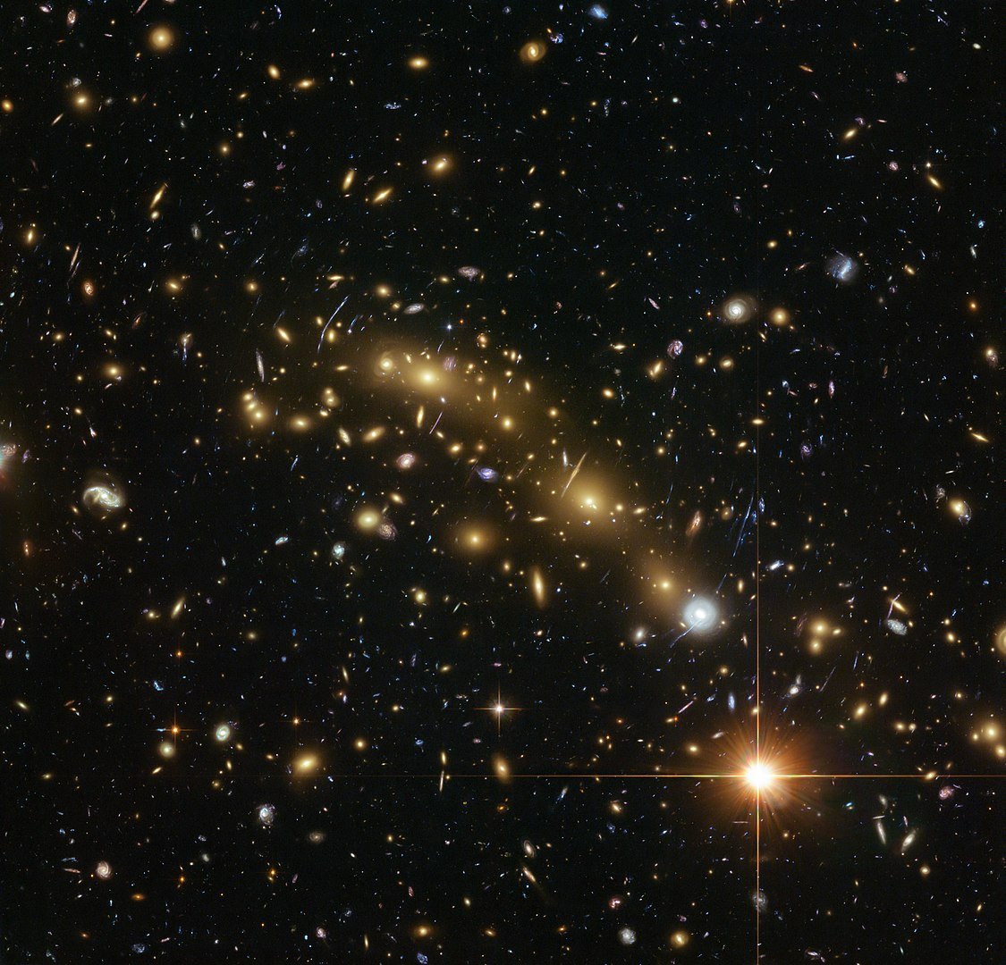 Imagen del gran cúmulo de galaxias MACS J0416.1-2403 donde vemos muchos arcos y formas alargadas en la parte central en color amarillo que se forman por el efecto de las lentes gravitacionales.